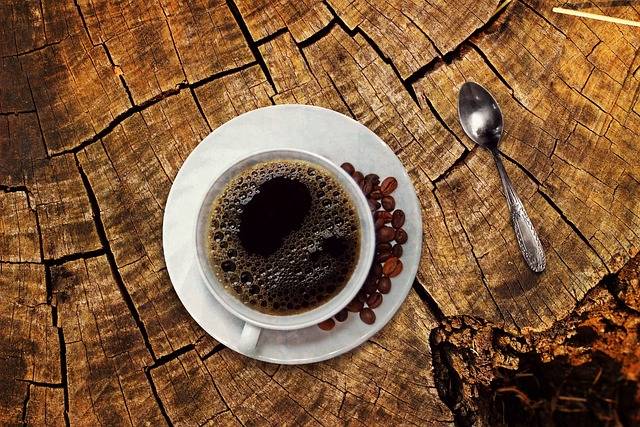Tasse de café noir et grains sur une table en bois brut