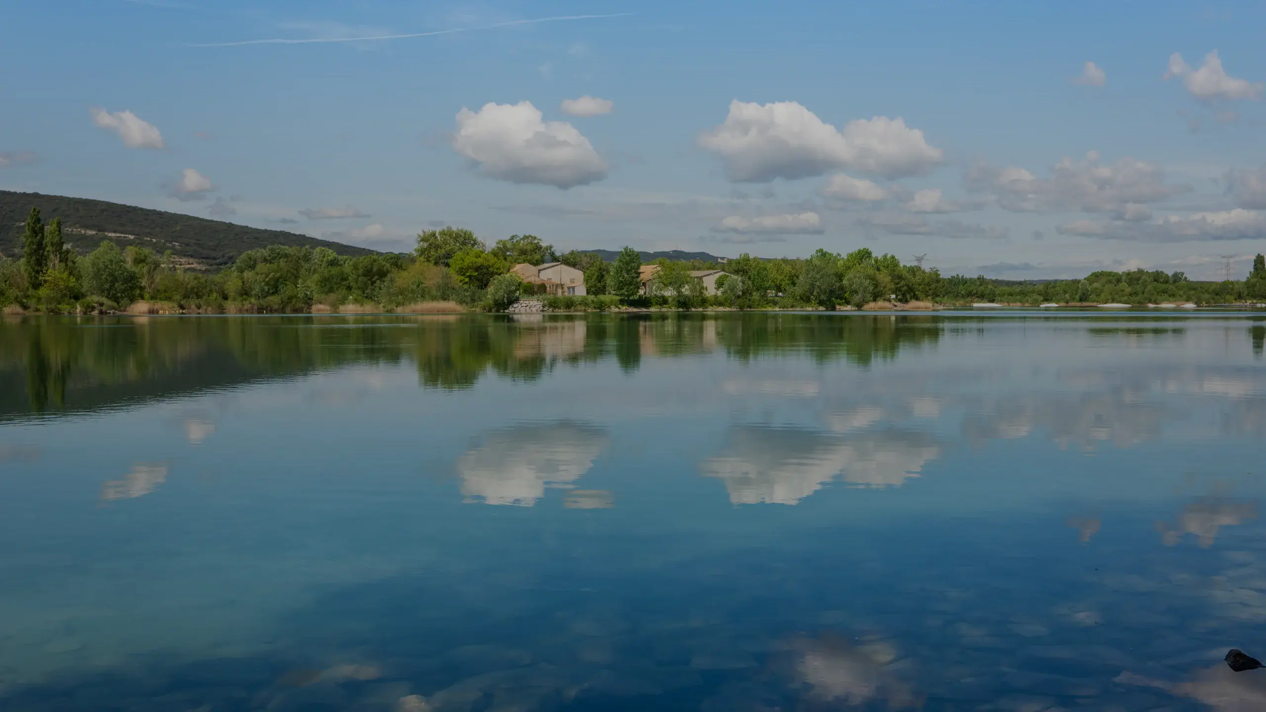 Un lac provençal aux eaux calmes sous un ciel d'été